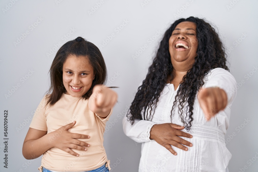 Mother and young daughter standing over white background laughing at you, pointing finger to the camera with hand over body, shame expression Mother and young daughter standing over white background laughing at you, pointing finger to the camera with hand over body, shame expression