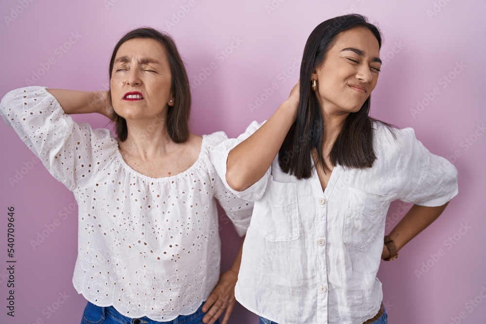 Hispanic mother and daughter together suffering of neck ache injury, touching neck with hand, muscular pain Hispanic mother and daughter together suffering of neck ache injury, touching neck with hand, muscular pain