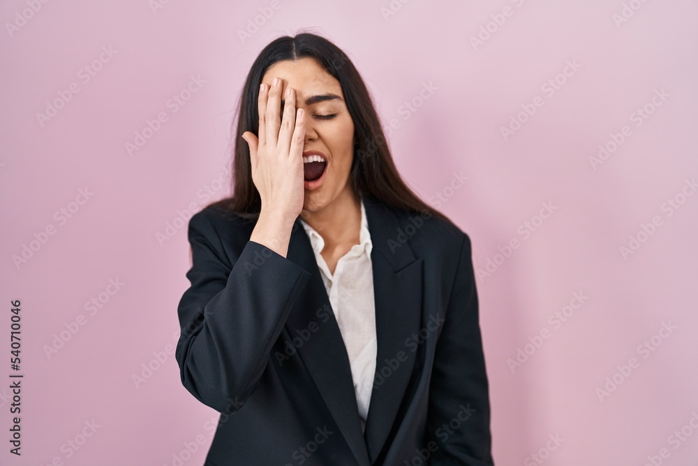 Young brunette woman wearing business style over pink background yawning tired covering half face, eye and mouth with hand. face hurts in pain. Young brunette woman wearing business style over pink background yawning tired covering half face, eye and mouth with hand. face hurts in pain.