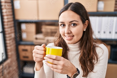 Young beautiful hispanic woman ecommerce business worker drinking coffee at office