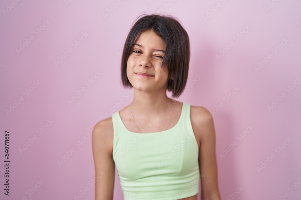 Young girl standing over pink background winking looking at the camera with sexy expression, cheerful and happy face. Young girl standing over pink background winking looking at the camera with sexy expression, cheerful and happy face.