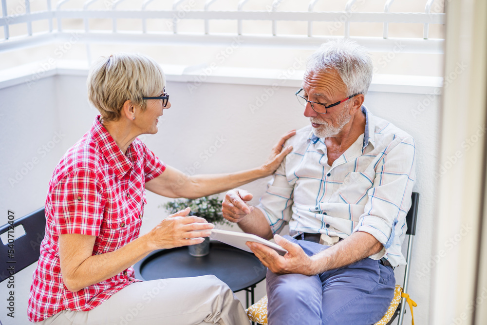 Obraz premium Senior couple sitting and talking on terrace at their home. Leisure time.