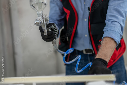 Craft person painting wood with a spray gun