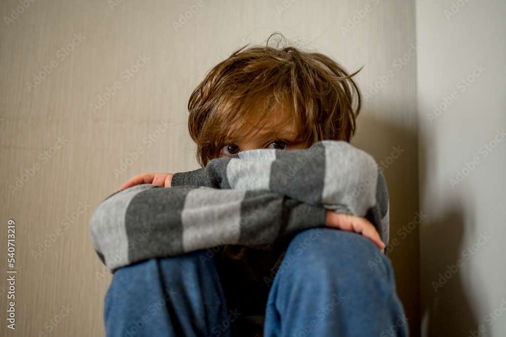 Sad boy sitting in corner at home Sad boy sitting in corner at home