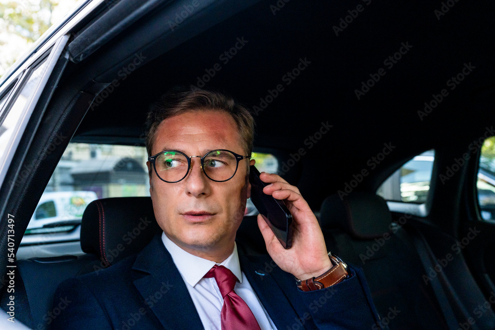 Businessman talking on smart phone sitting in car Businessman talking on smart phone sitting in car