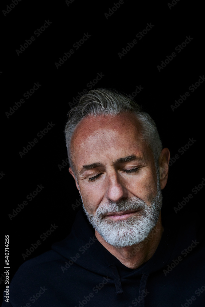 Mature man with eyes closed against black background Mature man with eyes closed against black background