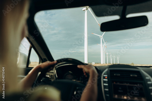 Hands of woman driving car at wind park photo