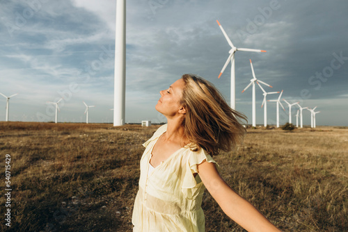 Carefree woman enjoying in front of wind turbines at field photo