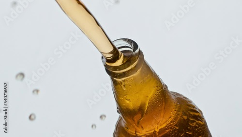 Opening glass ipa bottle closeup. Unfiltered beer splashing condensating flask photo