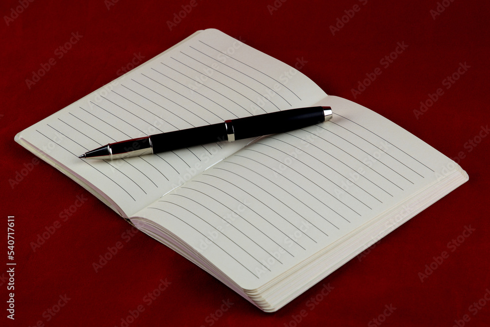 Open Notepad and Roller Ball Pen on a Red Table Cover Open Notepad and Roller Ball Pen on a Red Table Cover