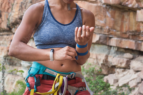 Strong female rock climber getting ready to climb with smart watch
