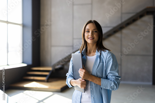 Obraz na plátně Successful young business woman holding laptop and standing in her office