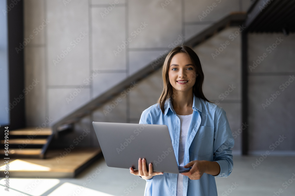 Portrait of smiling woman using laptop while standing at home Portrait of smiling woman using laptop while standing at home