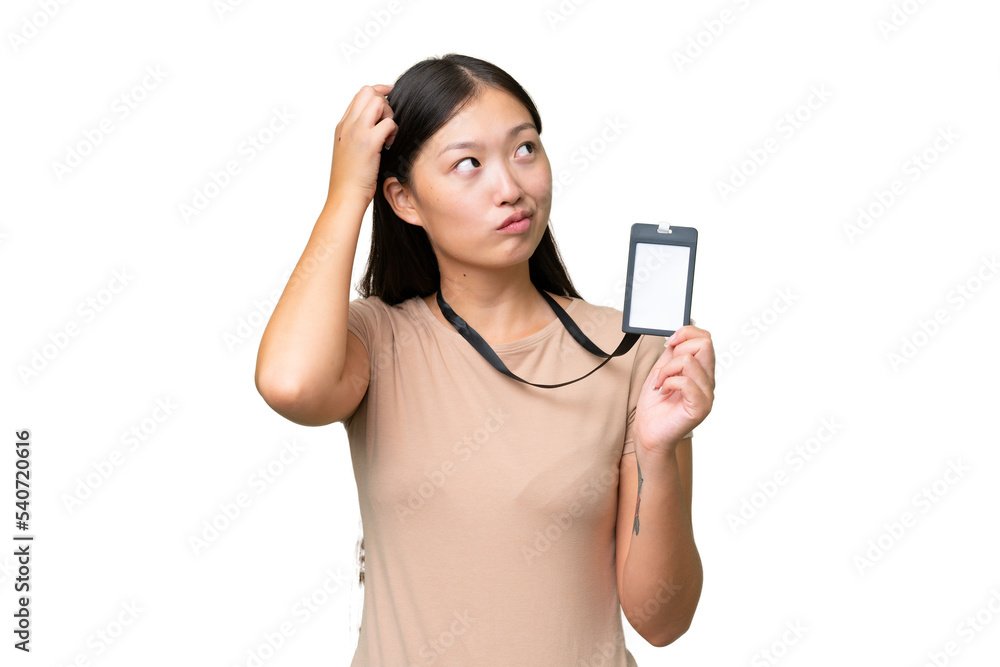 Young Asian woman with ID card over isolated background having doubts and with confuse face expression Young Asian woman with ID card over isolated background having doubts and with confuse face expression