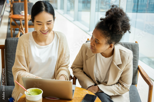 Fotografie Teamwork between professional asian woman employee with African woman intern wor