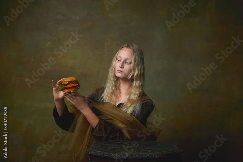 Strange thing. Vintage style portrait of young charming girl in image of Mona Lisa, La Gioconda looking at burger with surprise. Fast food, art, beauty, style, imitation