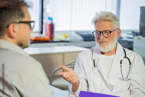 an elderly gray-haired male doctor in a medical office consults a male patient