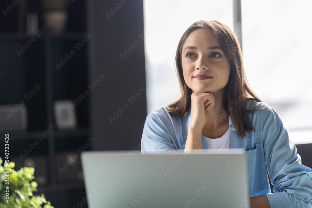 Young beautiful joyful woman smiling while working with laptop in office Young beautiful joyful woman smiling while working with laptop in office