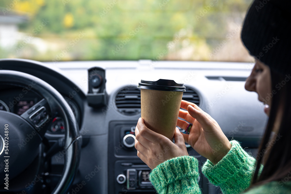 A young woman with a cup of coffee sits in the car, travel concept. A young woman with a cup of coffee sits in the car, travel concept.