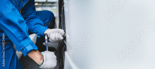 Auto mechanic checking tire condition, inspection and maintenance, mechanic using tools to check vehicle safety in garage, maintenance of damaged parts in garage.