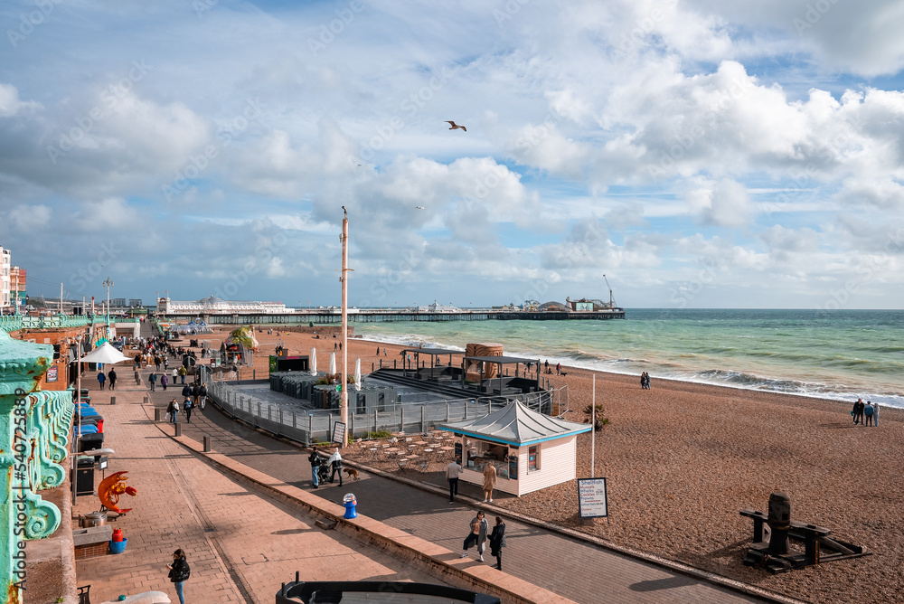 People walking down the promenade near the beach in Brighton. Holiday town by the sea. Enjoying Brighton vibe in England.
