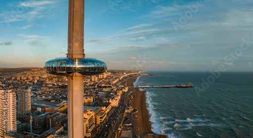 Magical sunset aerial view of British Airways i360 viewing tower pod with tourists in Brighton, UK with sea and Brighton Palace Pier in the background. photo