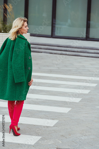 Obraz na płótnie Blonde woman in green warm coat crossing street.Back view. City female fashion w salonie