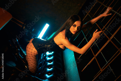 A sexy and beautiful woman enjoys a hookah in a nightclub. Glamorous clothes and neon lights.