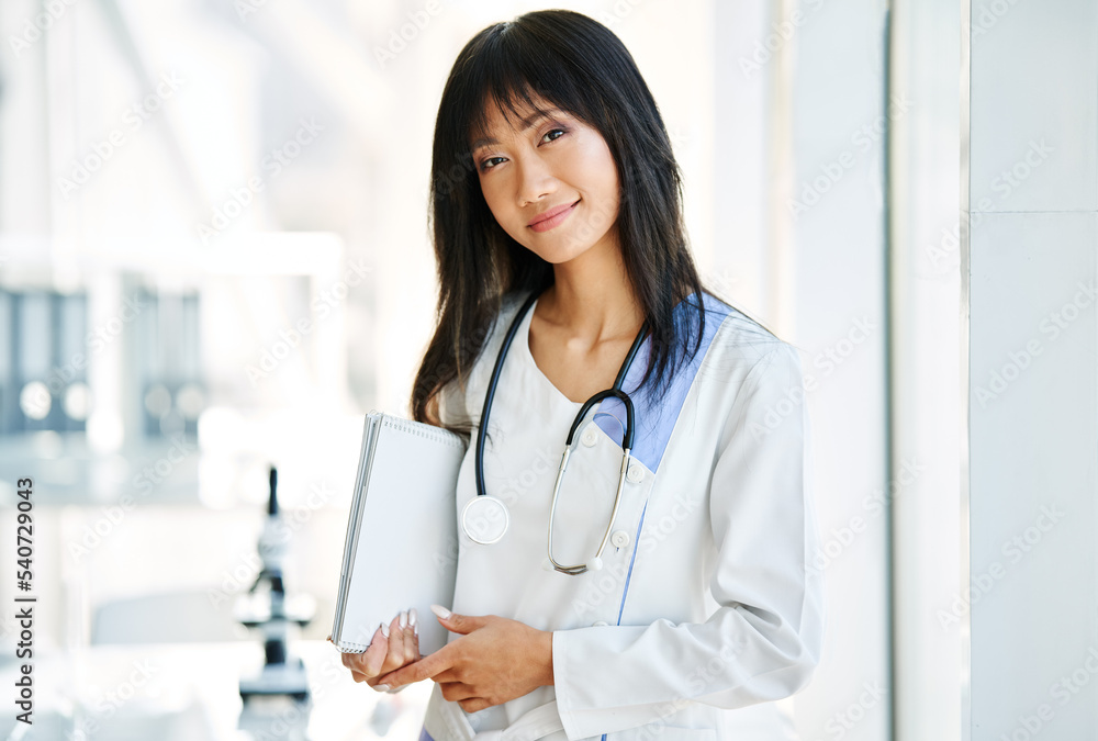 Smiling female asian doctor witn stethoscope wearing in lab coat looking to camera Smiling female asian doctor witn stethoscope wearing in lab coat looking to camera