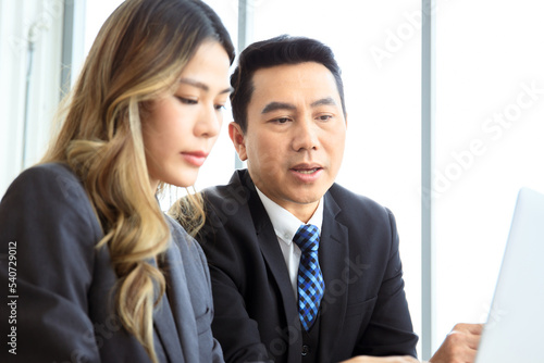 Asian businessman and businesswoman talking together in an office.