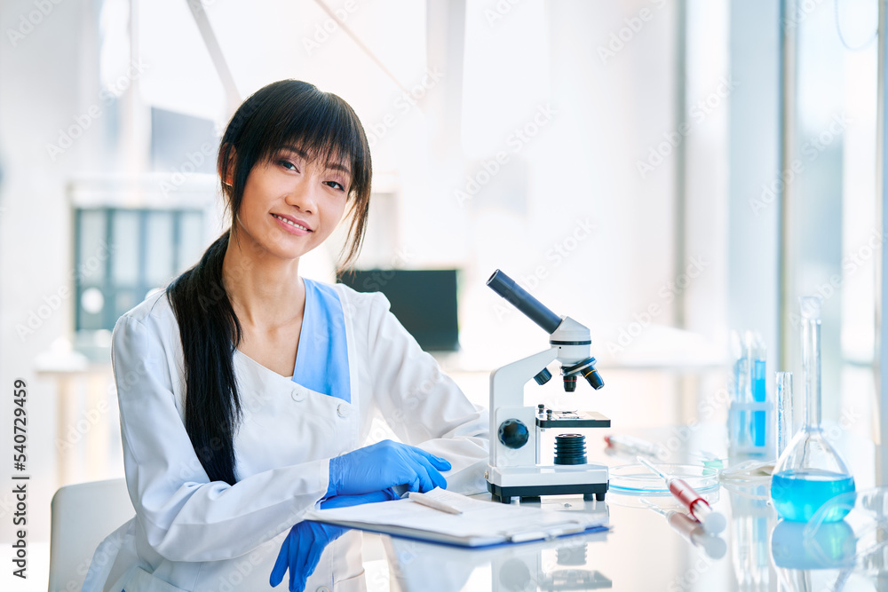 Smiling asian female scientist posing in modern medical research laboratory Smiling asian female scientist posing in modern medical research laboratory
