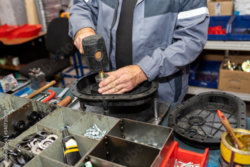 Industrial worker assembles agricultural equipment at plant photo