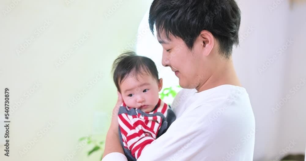 A young Asian father happily cradling his baby in his arms A young Asian father happily cradling his baby in his arms
