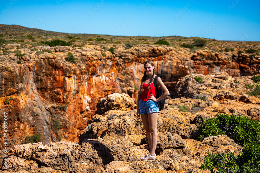 a long-haired girl sits on the edge of yardie creek gorge in cape range national park near exmouth in western australia, hiking in the wilderness of western australia