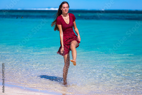 a beautiful long-haired girl in a dress soaks her feet in the turquoise water on a paradise beach at turquoise bay in cape range national park near exmouth, western australia © Jakub