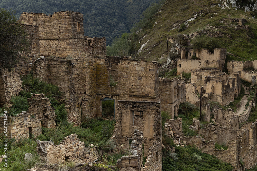 Ruin of old stone town on peak of in Caucasian mountains in Dagestan, fragments of destruction houses in medieval stone city in highlands. Majestic archeology adventure and tourist trip.