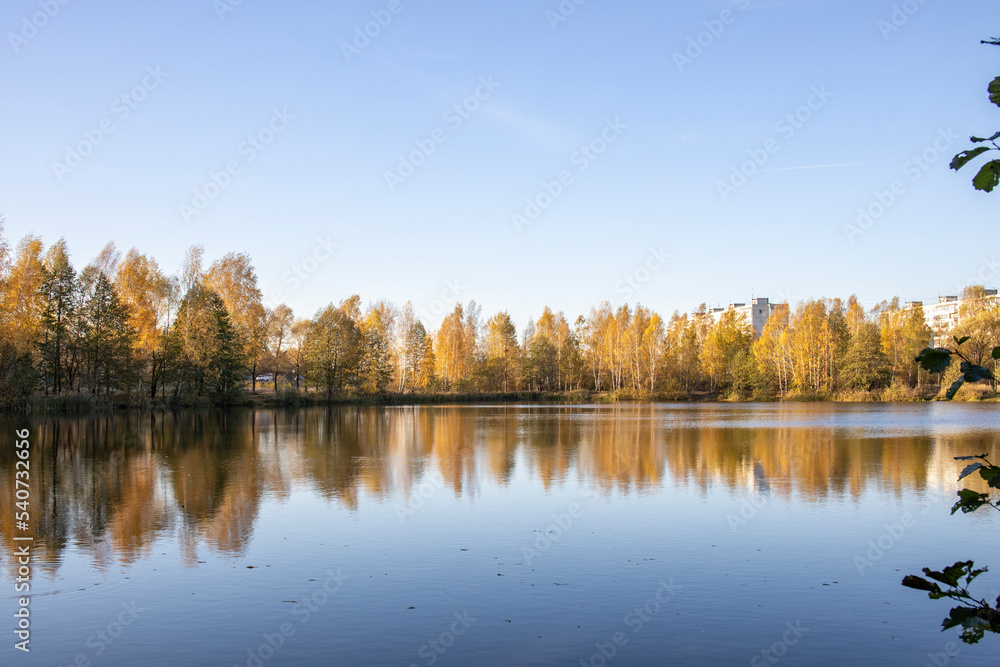 Autumn landscape with a pond. Trees with yellow foliage are reflected in the water. Autumn landscape with a pond. Trees with yellow foliage are reflected in the water.