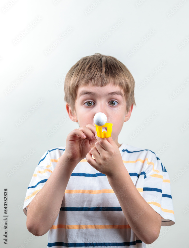 The boy breathes into a tube, holds the ball in the air. Breathing and speech simulator, eyes in a bunch. The boy breathes into a tube, holds the ball in the air. Breathing and speech simulator, eyes in a bunch.