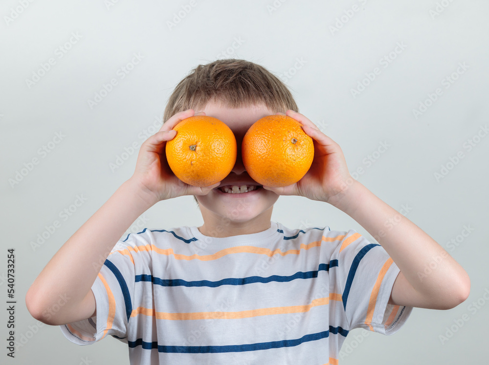 The boy holds oranges to his eyes. Orange eyes. Portrait. The boy holds oranges to his eyes. Orange eyes. Portrait.