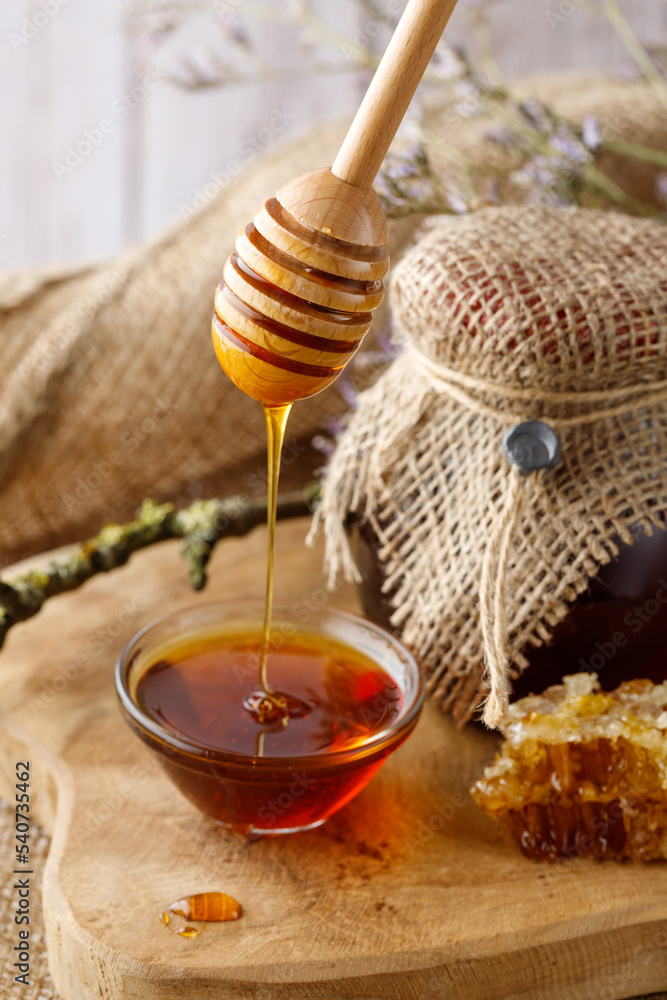 Wooden dipper with flowing fresh natural honey. Fresh harvesting brown forest honey in glass bowl and jar. Healthy dessert. Wooden dipper with flowing fresh natural honey. Fresh harvesting brown forest honey in glass bowl and jar. Healthy dessert.