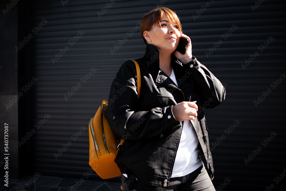Plus size woman dressed jacket, jeans and t-shirt posing against wall in the street Plus size woman dressed jacket, jeans and t-shirt posing against wall in the street
