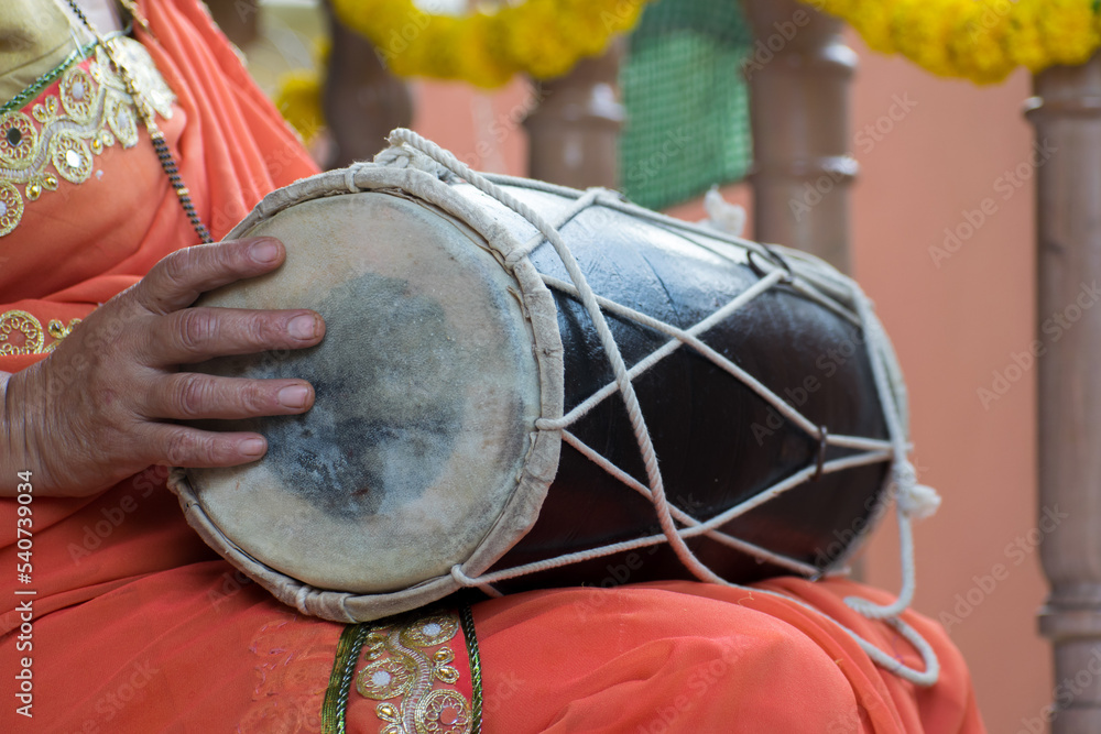 Hand of Indian woman playing dhol, dholak, dholki, drum during festival, celebration, event, ladies sangeet, mehendi party. Indian culture, traditional, dance, music, player, friends, gidda, punjabi 