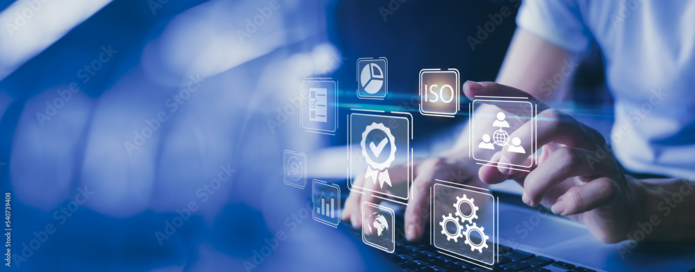 © Montri - Businessman working on laptops with signs of the top service Quality control certification, ISO, checked guarantees of the standard of company product. Concept on virtual screen.