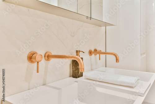 Interior of minimalist bathroom with shower and sink with copper faucets