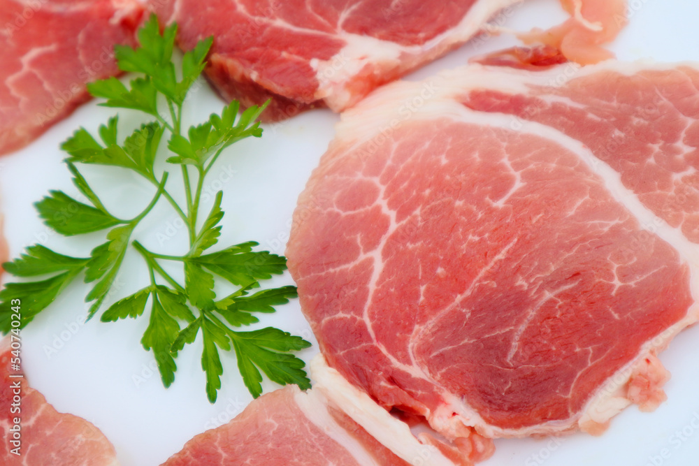 Raw Pork Slice in White Round Plate decorated with parsley. Fresh raw pork. Raw Pork Slice in White Round Plate decorated with parsley. Fresh raw pork.