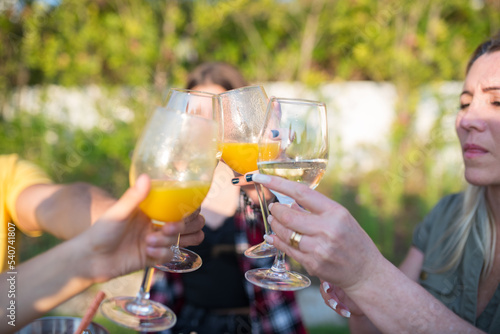 Close-up of family clinking glasses over table. Mid adult parents and children sitting around table, raising flutes with different beverages. BBQ, cooking, food, family concept