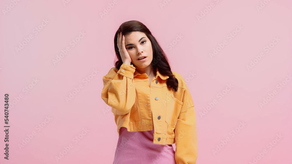 tired young woman in orange denim jacket looking at camera isolated on pink tired young woman in orange denim jacket looking at camera isolated on pink