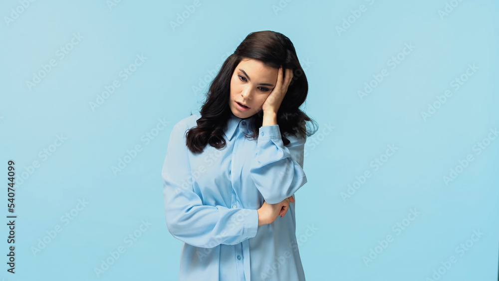 dissatisfied woman in shirt touching head and puffing cheeks isolated on blue dissatisfied woman in shirt touching head and puffing cheeks isolated on blue