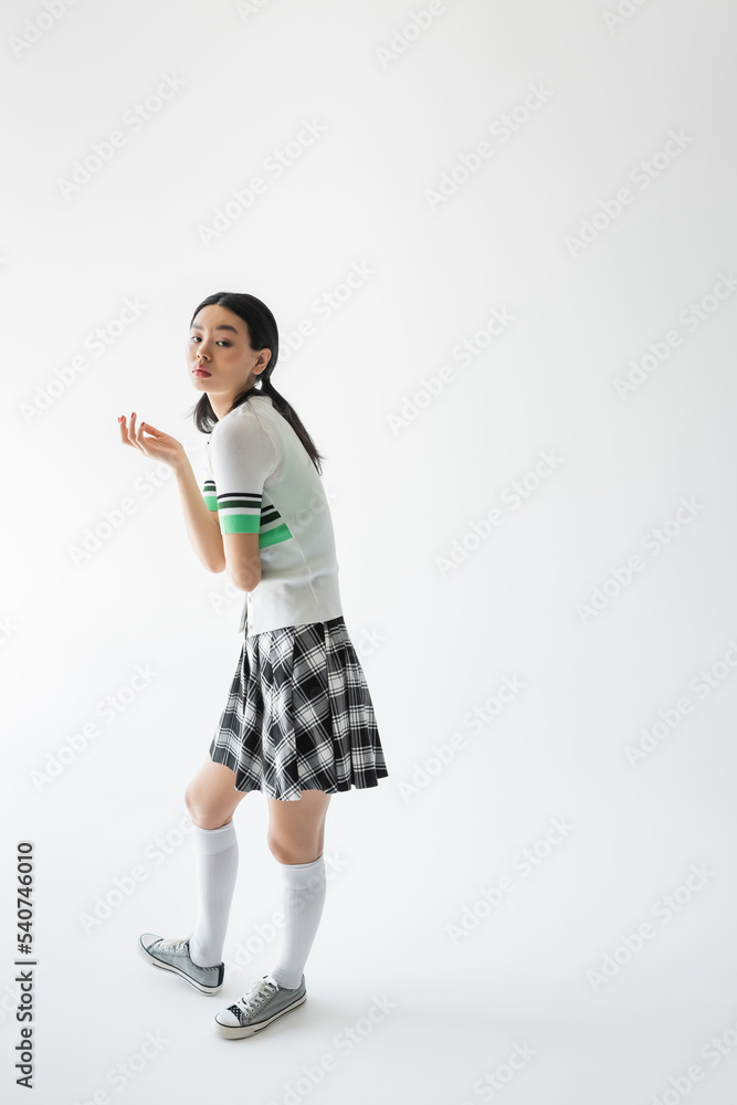 Full length of stylish asian woman looking at camera on grey background Full length of stylish asian woman looking at camera on grey background