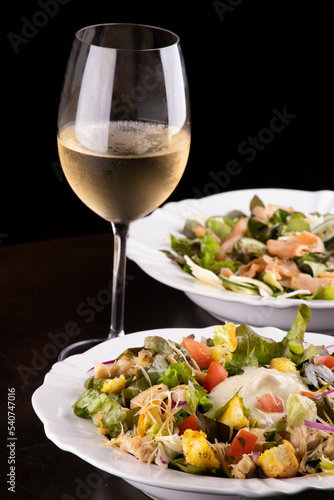 two plates of salad and a glass of white wine on wooden table healthy eating close-up macro
